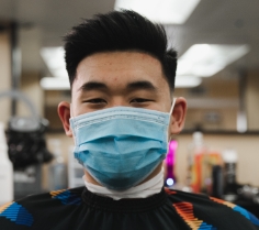 An Asian man wearing a mask after his haircut